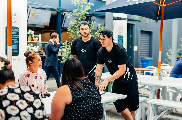 The owners of Ika Bowl talking to customers at a table