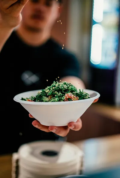 The co-founder of Ika Bowl sprinkling seaseme seeds on a Ika Bowl